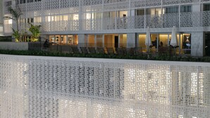 Hotel com design arquitetônico moderno, fachada treliçada e várias varandas.