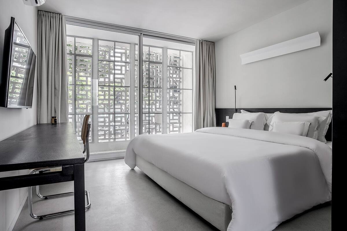 A modern hotel room with a large bed, a desk, and a TV.