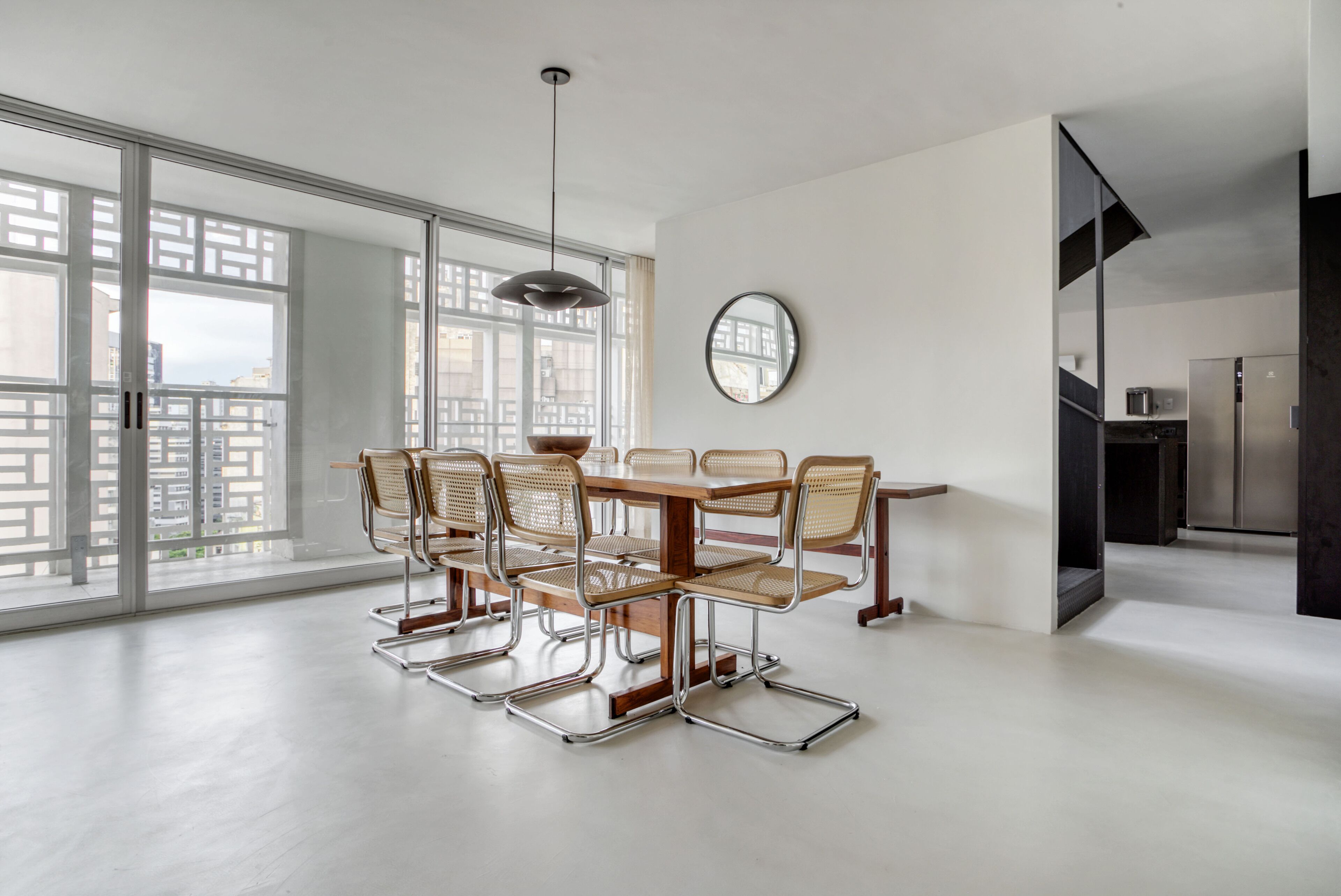 Un comedor moderno con una mesa y sillas de madera, ventanas amplias y vistas a la ciudad.