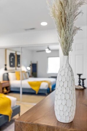 Un florero blanco con un diseño texturizado sobre una mesa de madera en un dormitorio moderno.