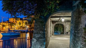 A stone archway leading to a courtyard with a boat docked nearby. - 2 Rooms in a  wonderful villa, with lake view (Perledo)