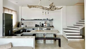 A modern kitchen with a central island, built-in appliances, and a unique ceiling sculpture.