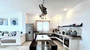 A modern kitchen with a central island, built-in appliances, and a dining area with a bench.