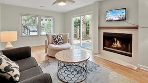 Ein Wohnzimmer mit Kamin, Deckenventilator, Fernseher und einer Couch.