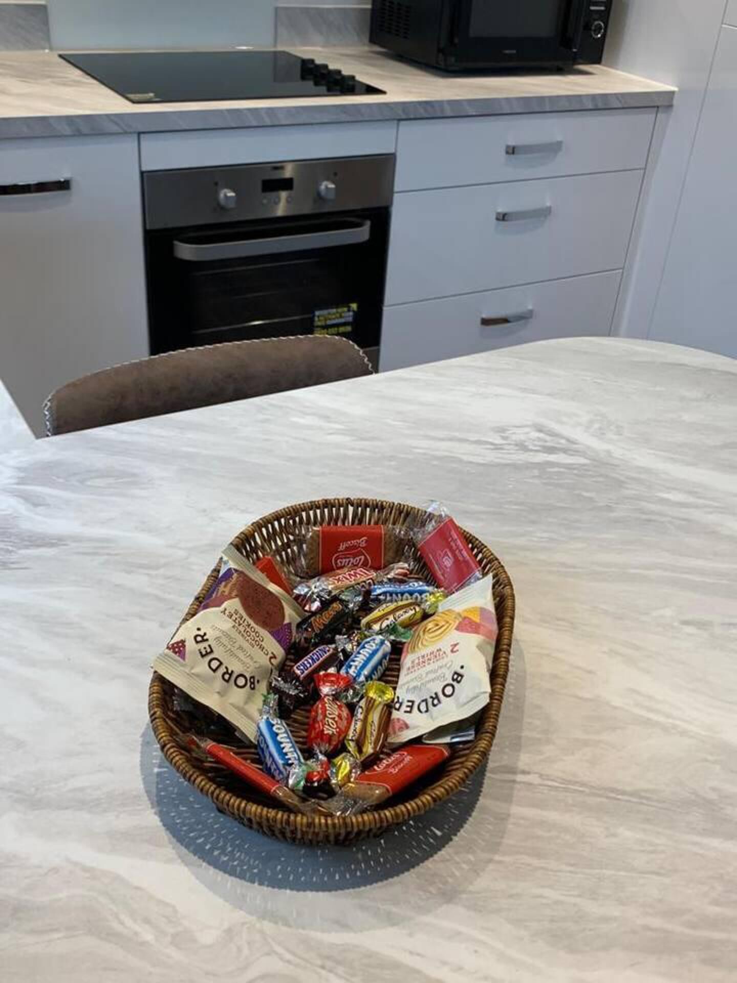 Una cocina con microondas, horno y un cesto de aperitivos en la encimera.