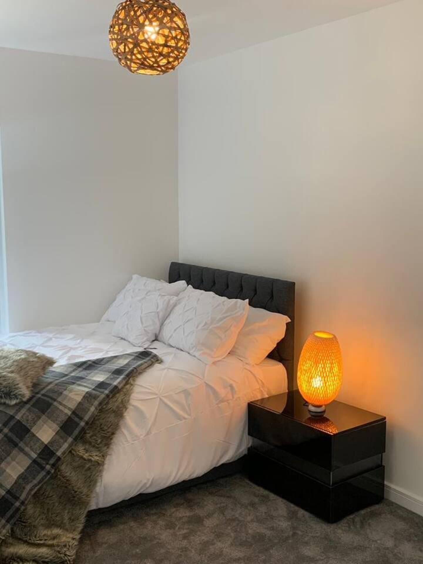 A bedroom with a bed, a nightstand, and a wall-mounted lamp.