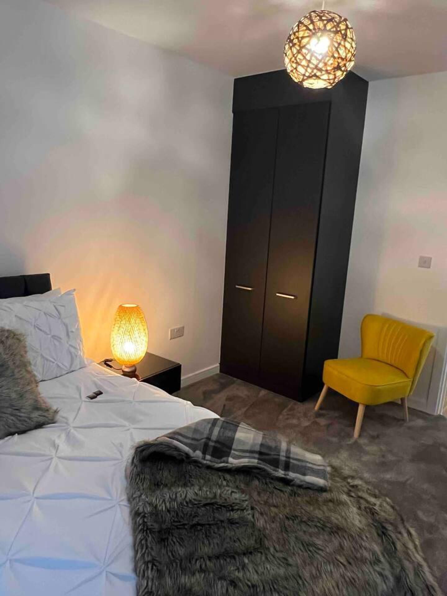 Une chambre à coucher comprenant un lit, une table de chevet, une lampe, une armoire et une chaise.
