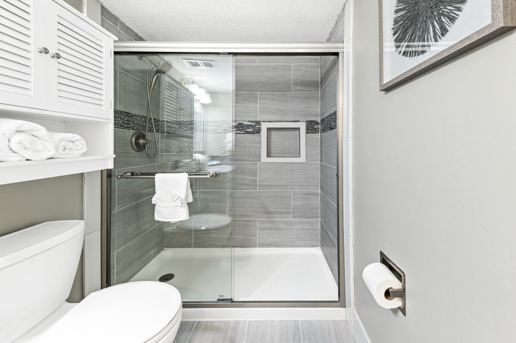 A modern bathroom with a glass-enclosed shower, a toilet, and a towel rack.