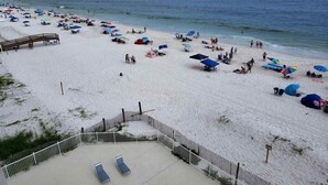 Une plage avec des parasols, des chaises longues et une terrasse en bois.