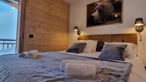 Ein gemütliches Schlafzimmer mit einem Holzkopfteil, einem großen Bett mit vielen Kissen und einem aufgehängten Bild eines Bären.