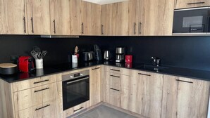 Eine moderne Küche mit Holzausstattung, einer schwarzen Arbeitsplatte und Edelstahlgeräten, darunter eine Bosch Mikrowelle und ein Backofen.
