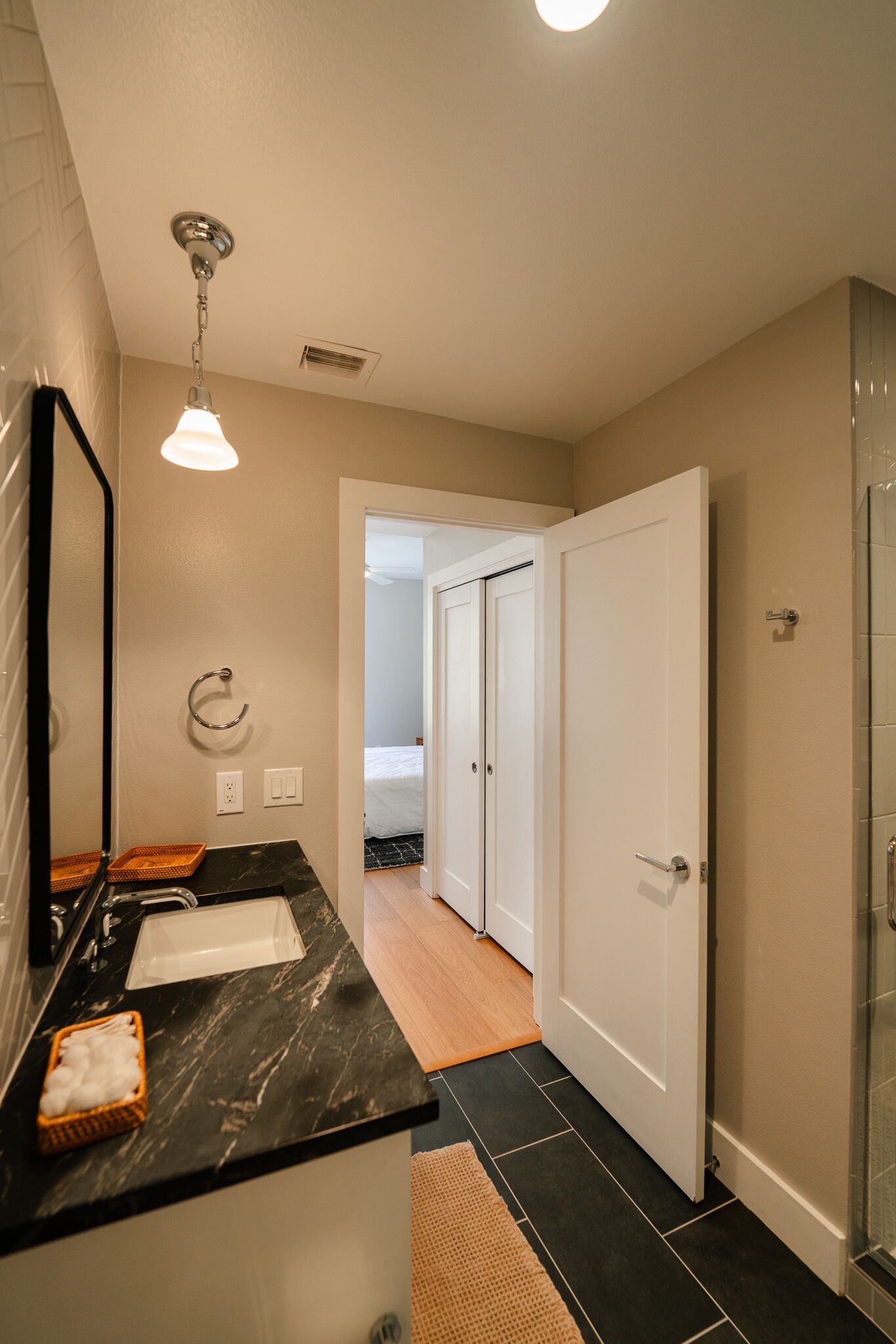 A bathroom with a black marble sink, a mirror, a towel ring, and a shower area.