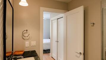 A bathroom with a black marble sink, a mirror, a towel ring, and a shower area.