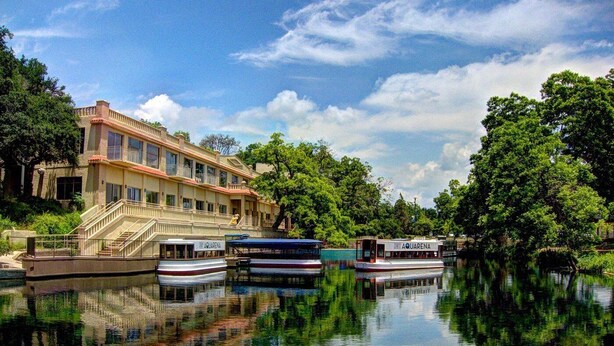 Ein Hotel mit einem großen Gebäude, Spiegelungen im Wasser und Booten.