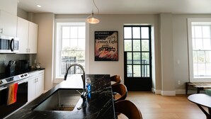 Eine moderne Küche mit Marmorarbeitsplatte, Edelstahlgeräten und einem großen Fenster.