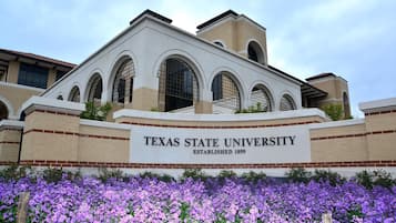 Texas State University building with arched windows and a sign stating its establishment year.