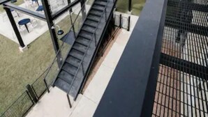 Eine Metalltreppe führt zu einem Außenbereich mit Tischen und Stühlen.
