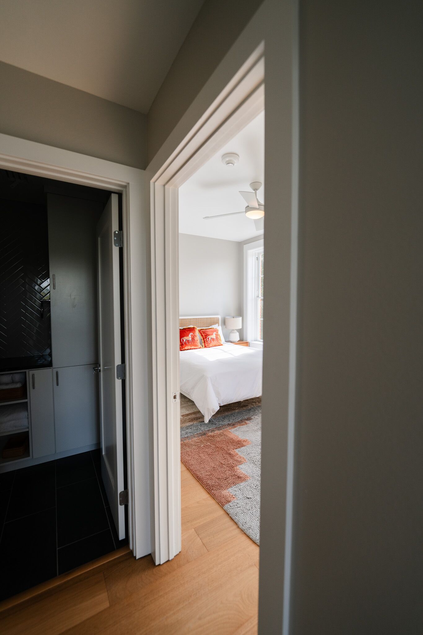 Un couloir menant à une chambre à coucher équipée d’un lit, d’une table de chevet et d’une lampe.