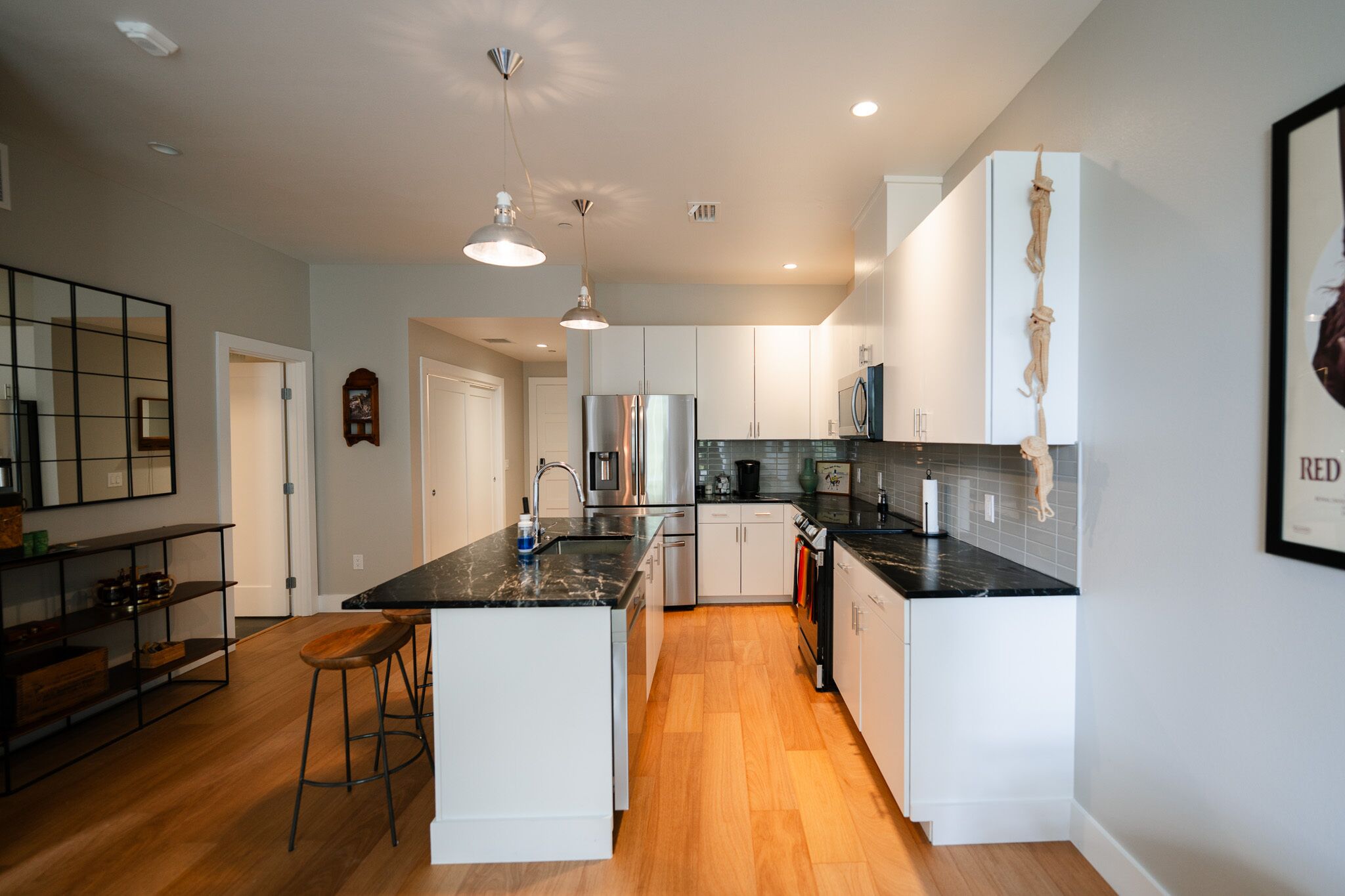 A modern kitchen with white cabinetry, a central island, stainless steel appliances, and wooden flooring.