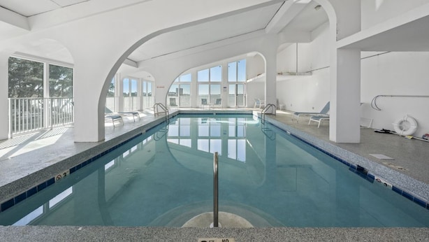 An indoor swimming pool with clear glass walls, a tiled floor, and a no diving sign.