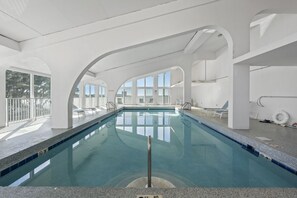 An indoor swimming pool with clear glass walls, a tiled floor, and a no diving sign. - Compass  Point  108 (Gulf Shores)