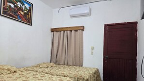 A room with two beds, a wooden door, an air conditioning unit, and a painting on the wall. - Hotel Villa Aurora (Flores)