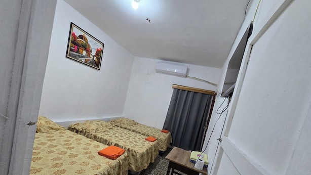 A small, compact room with two single beds, a small table, a curtain, and a ceiling light. - Hotel Villa Aurora (Flores)
