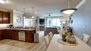 Een moderne keuken met houten kastjes, een vaatwasser en een eethoek met een witte tafel en stoelen.