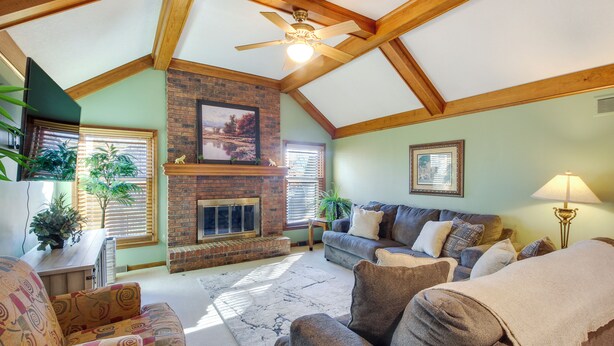 A cozy living room with a fireplace, wooden beams, and comfortable seating. - Overland Park Family Home w/ Game Room & Backyard! (Overland Park)