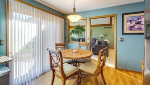 A dining area with a round wooden table, four chairs, and a hanging light fixture. - Overland Park Family Home w/ Game Room & Backyard! (Overland Park)