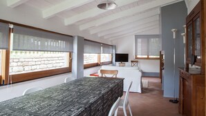 A room with a bed, a TV, and a dining table with chairs. - Apartment for 5 People with Pool (Isola Di Fano)