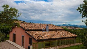 A small, single-story building with a tiled roof and a wooden fence. - Apartment for 5 People with Pool (Isola Di Fano)