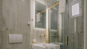 A modern bathroom with a toilet, sink, and glass-enclosed shower. - San Rocco Suite #3 by Corfu Collection
 (Kerkira)