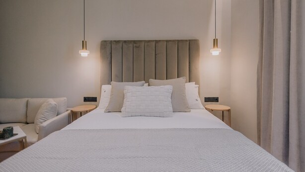 A modern hotel room with a large bed, two bedside tables, a nightstand, and a sofa. - San Rocco Suite #3 by Corfu Collection
 (Kerkira)