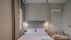 Une chambre moderne avec un grand lit, des tables de chevet, un canapé et un appareil de climatisation.