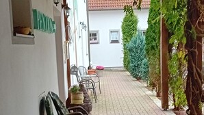 An outdoor patio with a table and chairs, a pergola overhead, and a pathway leading to a building. - Pension u Dubu (Frantiskovy Lazne)