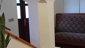 A room with a wooden bench, a potted plant, and a patterned sofa. - Pension u Dubu (Frantiskovy Lazne)