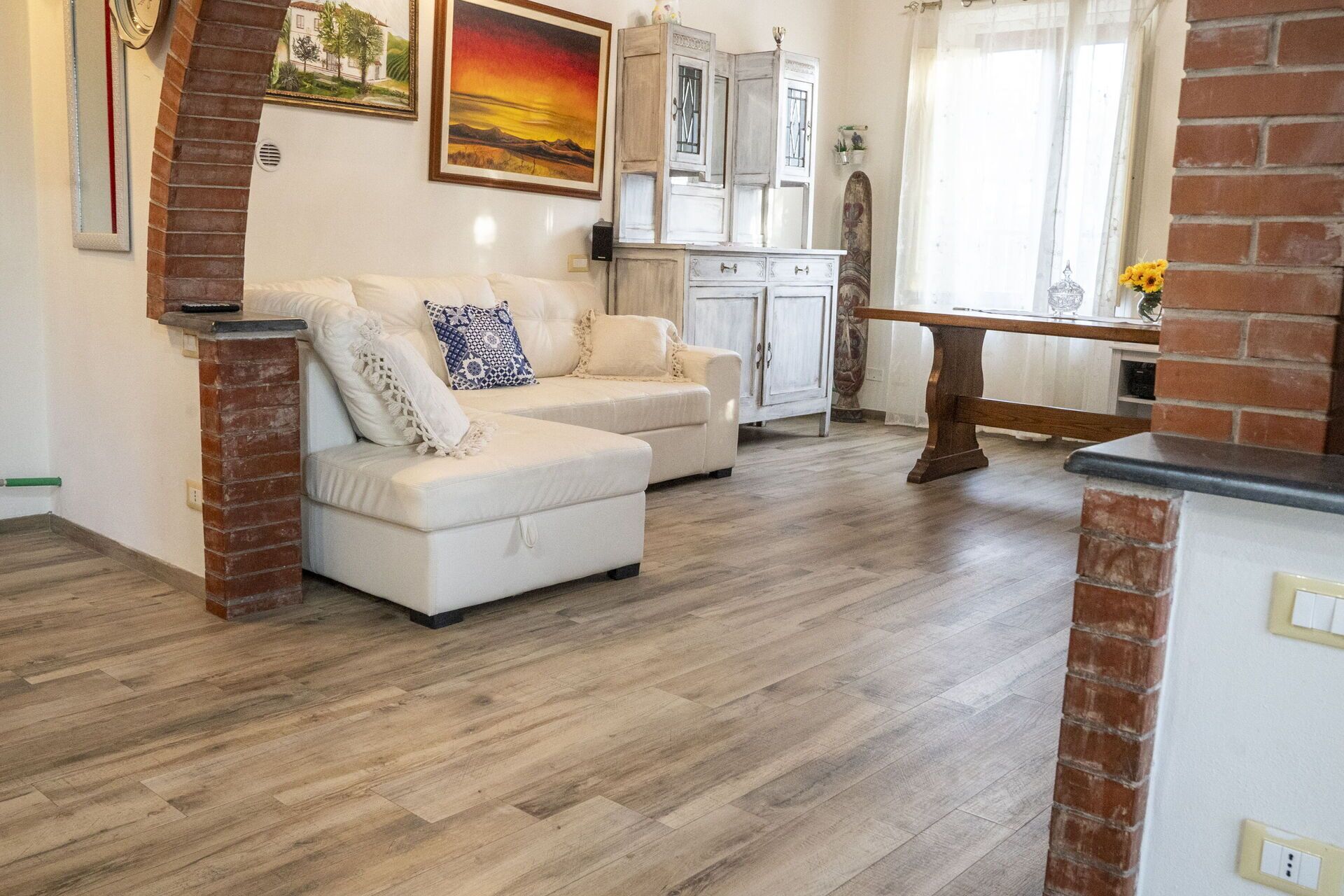 A living room with a white sofa, a wooden coffee table, and a brick fireplace.