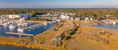 An aerial view of a marina with boats docked, a large building, and surrounding residential areas.