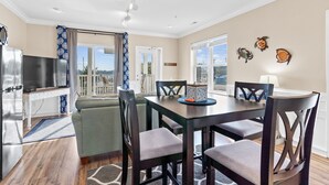 Un comedor con mesa y sillas, televisor y vistas al exterior.