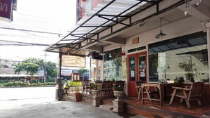 A cafe with outdoor seating, a red door, and a covered patio area. - RTW Residence (Bangkok)