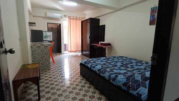 A bedroom with a bed, a television, a desk, and a chair.