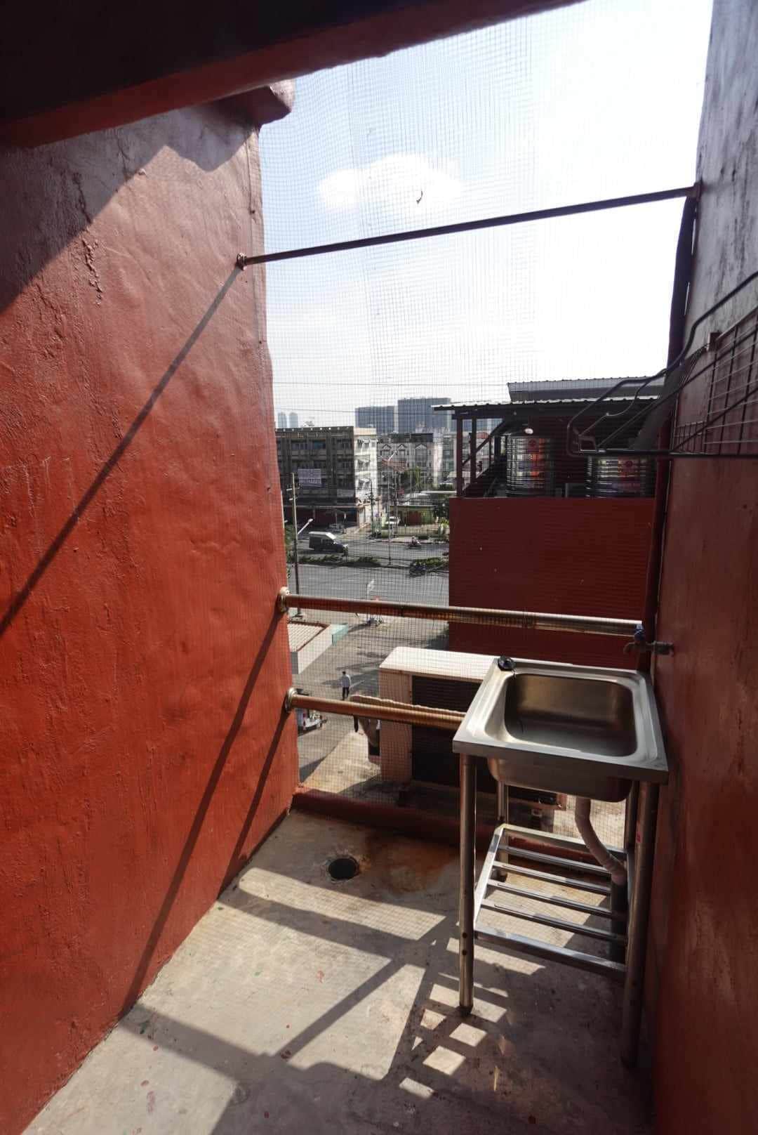 Un petit balcon avec un évier en métal et une rambarde en métal.