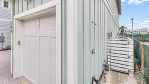 A white garage door with a metal handle, a white door frame, and a small step leading up to a wooden deck. - Palm Palace 209 STA (Port Aransas)