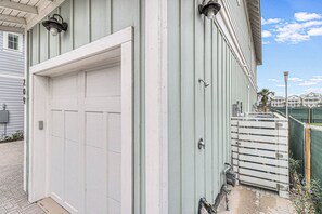 A white garage door with a metal handle, a white door frame, and a small step leading up to a wooden deck. - Palm Palace 209 STA (Port Aransas)