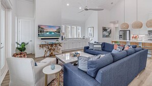 A spacious living room with a large blue sofa, a coffee table, and a television on the wall. - Palm Palace 209 STA (Port Aransas)