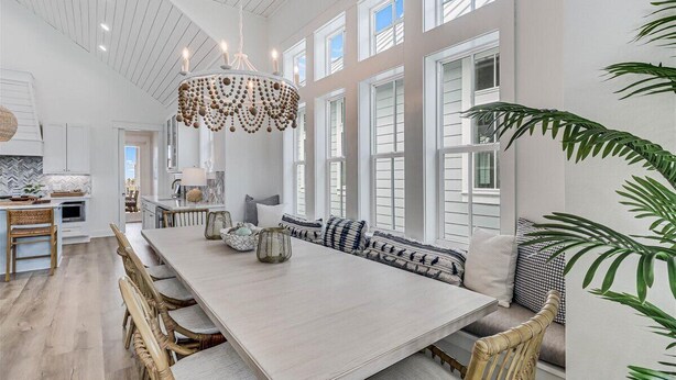A spacious dining area with a long table, wicker chairs, and a decorative chandelier. - Palm Palace 209 STA (Port Aransas)