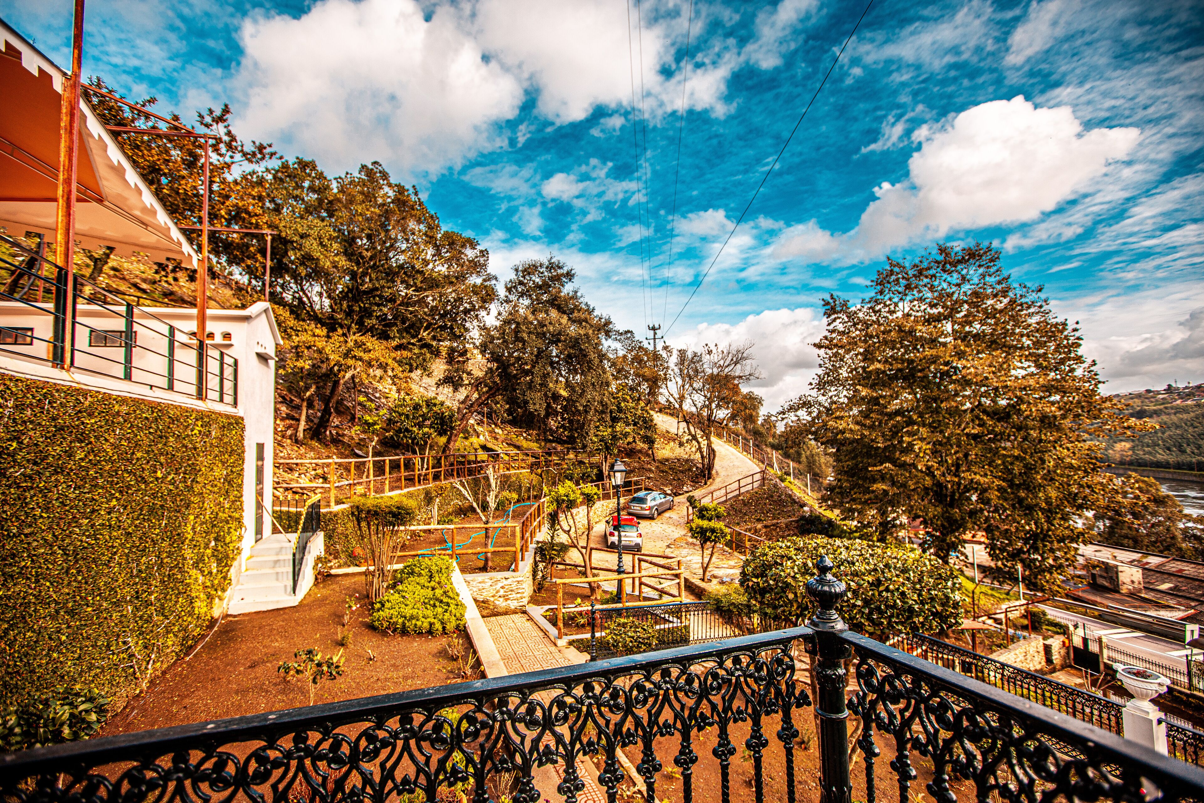 A hillside residential area with a staircase leading to a house, surrounded by trees and a clear sky.