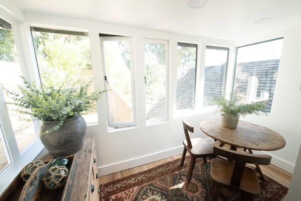 A room with a large window, a wooden table, a chair, and a potted plant.