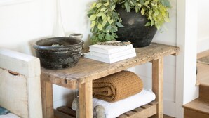 Una mesa de madera rústica con una planta en maceta, un tazón y libros.